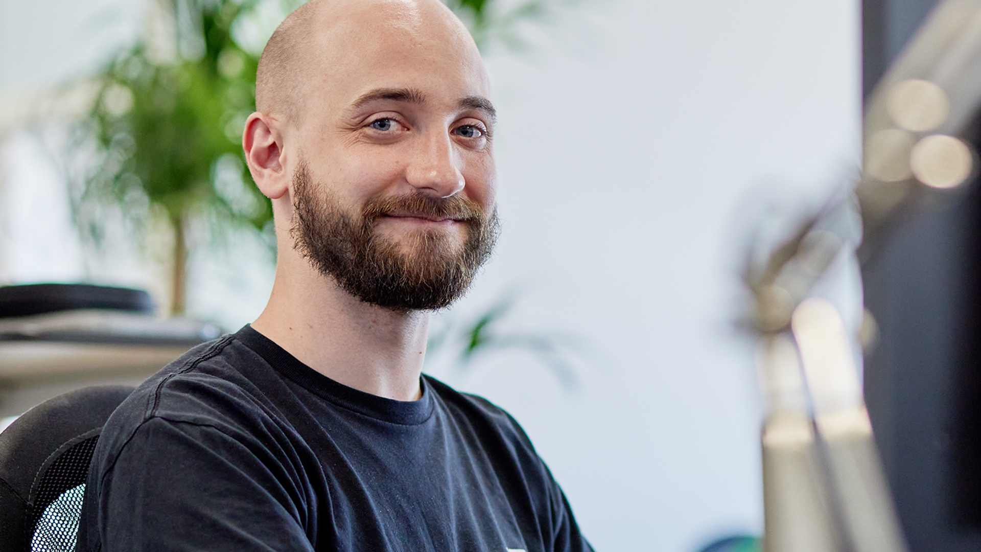 Martin Stadelmann mit schwarzem T-Shirt sitzend auf Bürostuhl