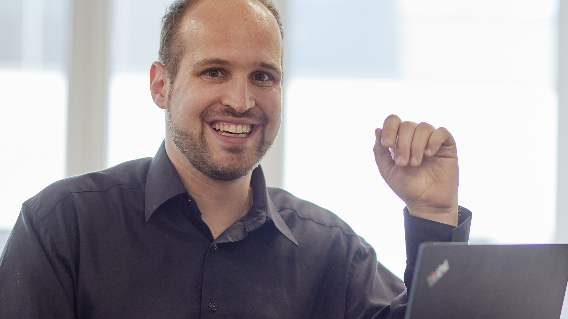 Adrian Aellig mit schwarzem Hemd vor Laptop