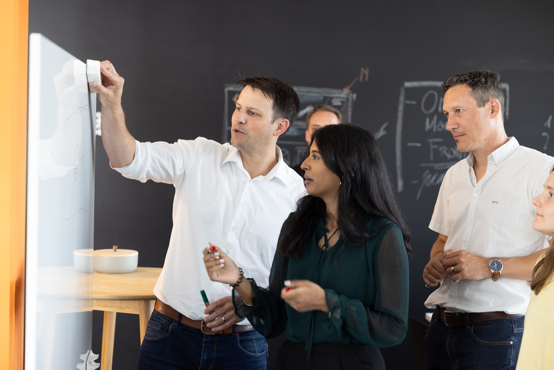 iqual Mitarbeitende stehen vor einen Whiteboard