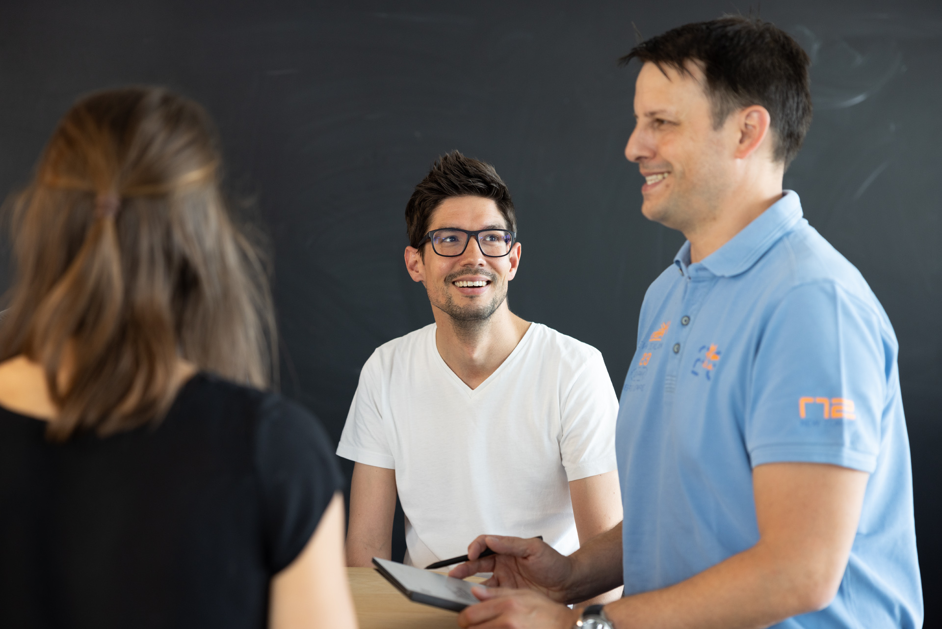 iqual Mitarbeitende stehen an einem Tisch