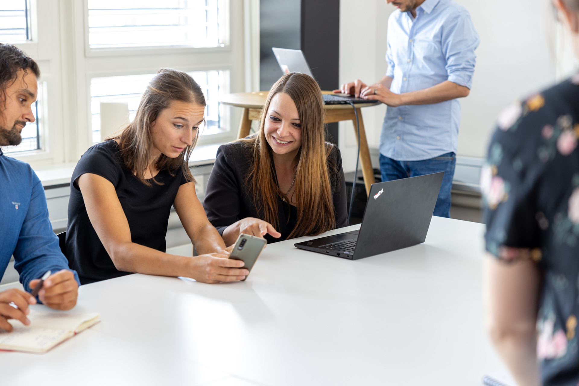 iqual Mitarbeitende schauen auf ein Smartphone