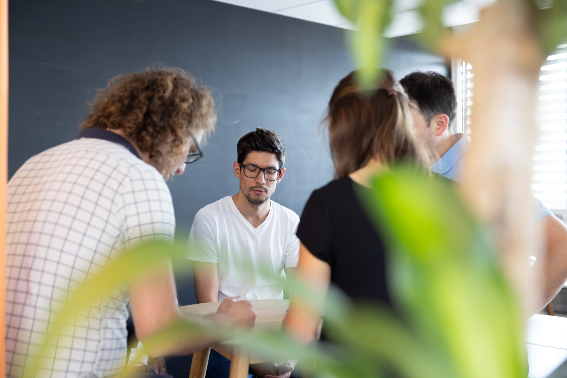 iqual Mitarbeitende stehen an einem Tisch