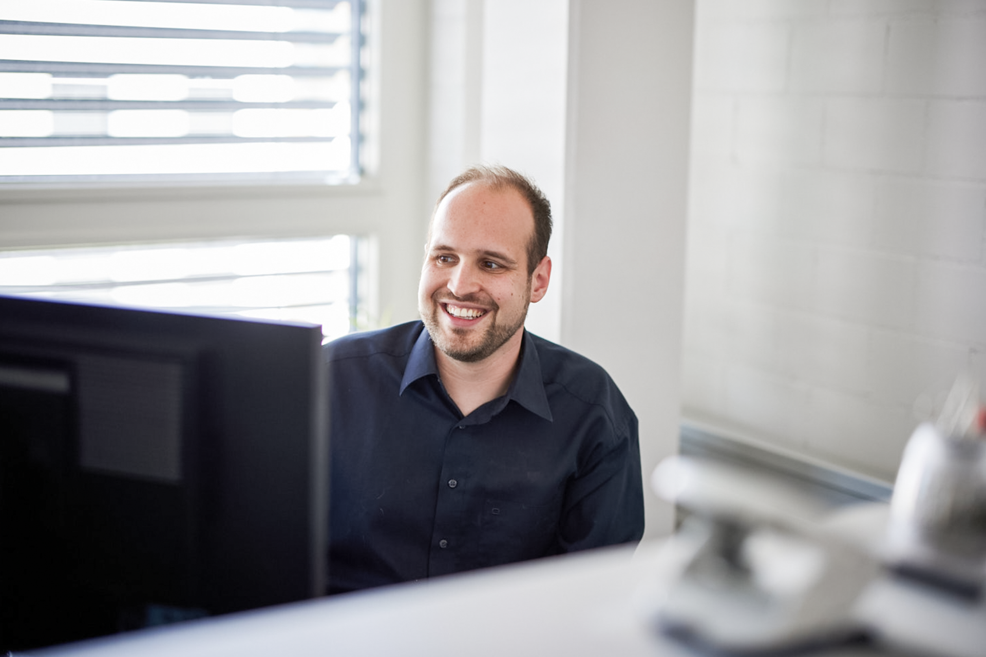 iqual Mitarbeiter lacht vor Bildschirm