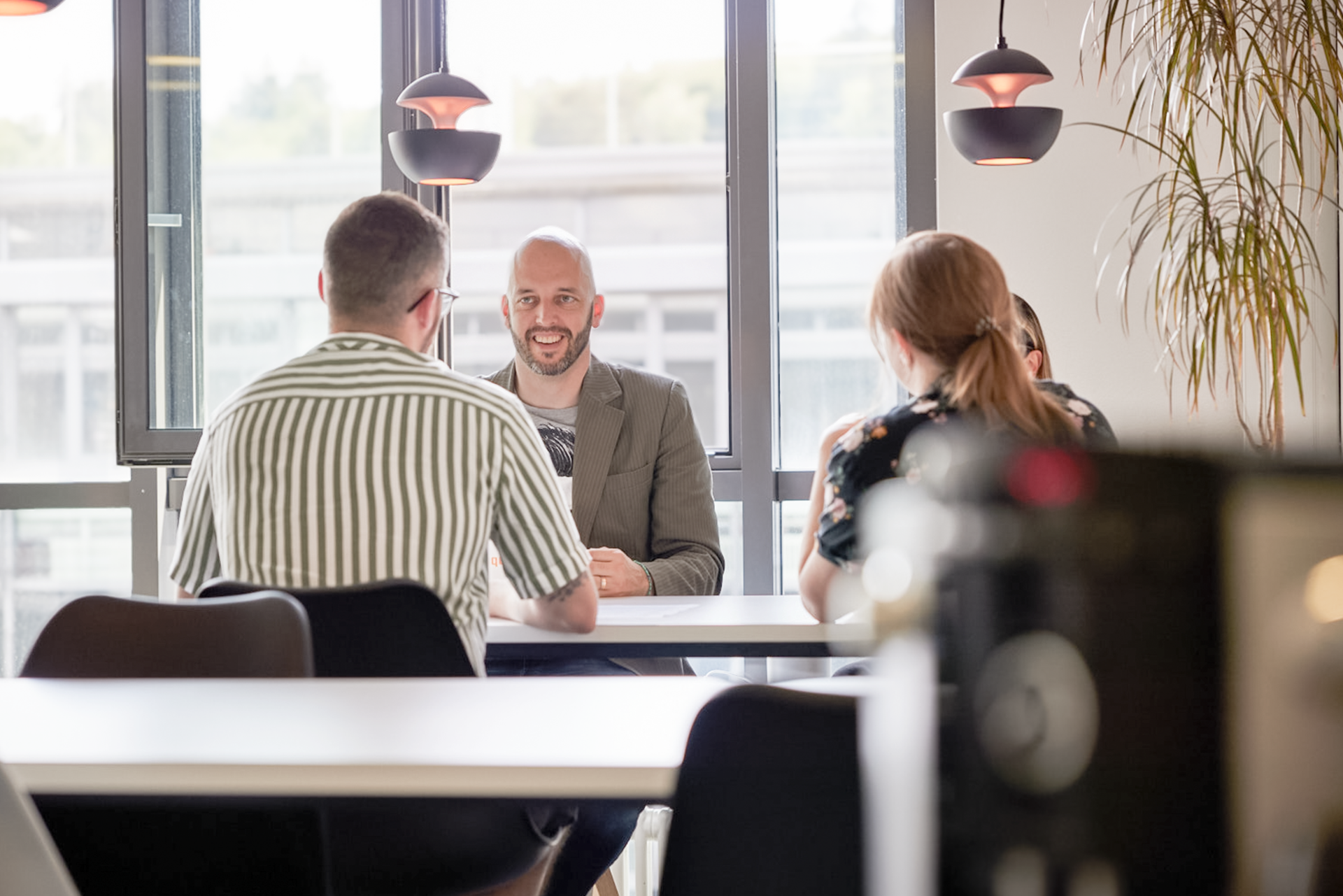iqual Mitarbeitende sitzen am Tisch