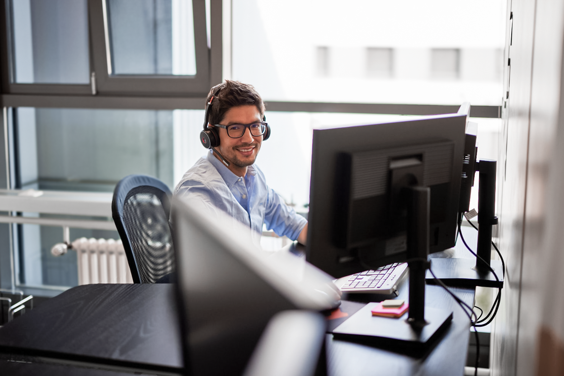 iqual Mitarbeiter sitzt mit Kopfhörern am PC