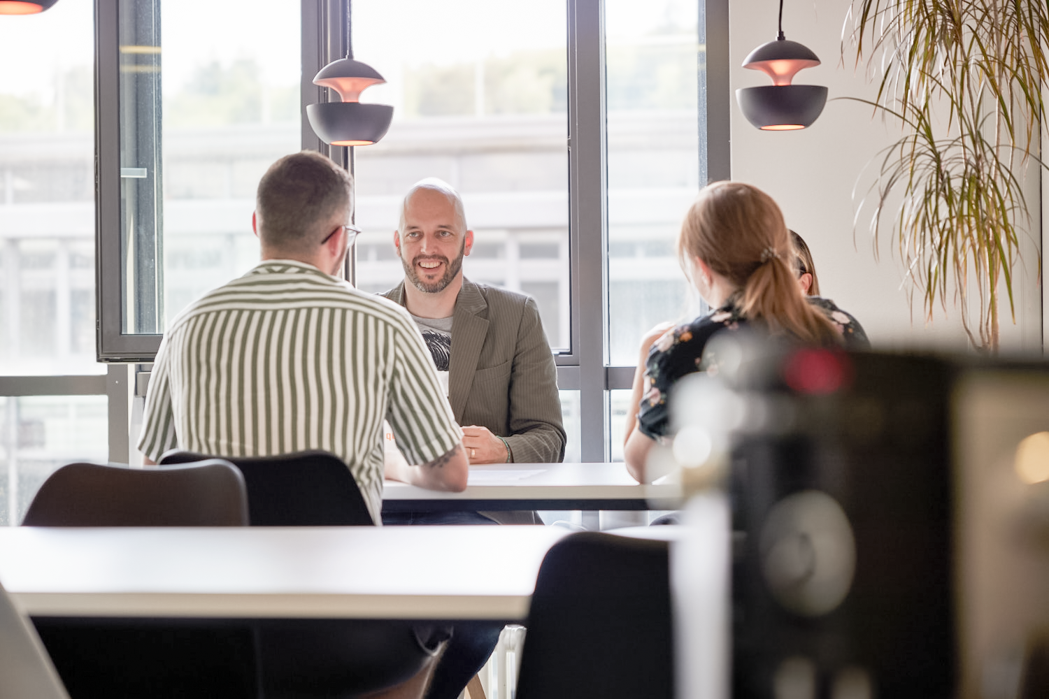 iqual Mitarbeitende sitzen am Tisch und unterhalten sich