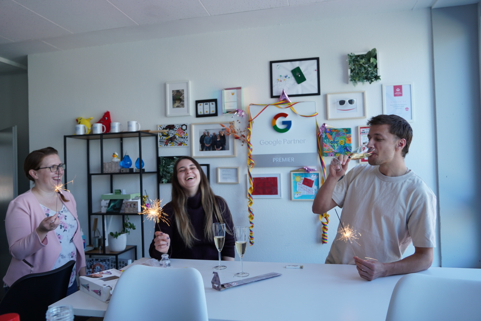iqual Mitarbeitende lachen und trinken Sekt