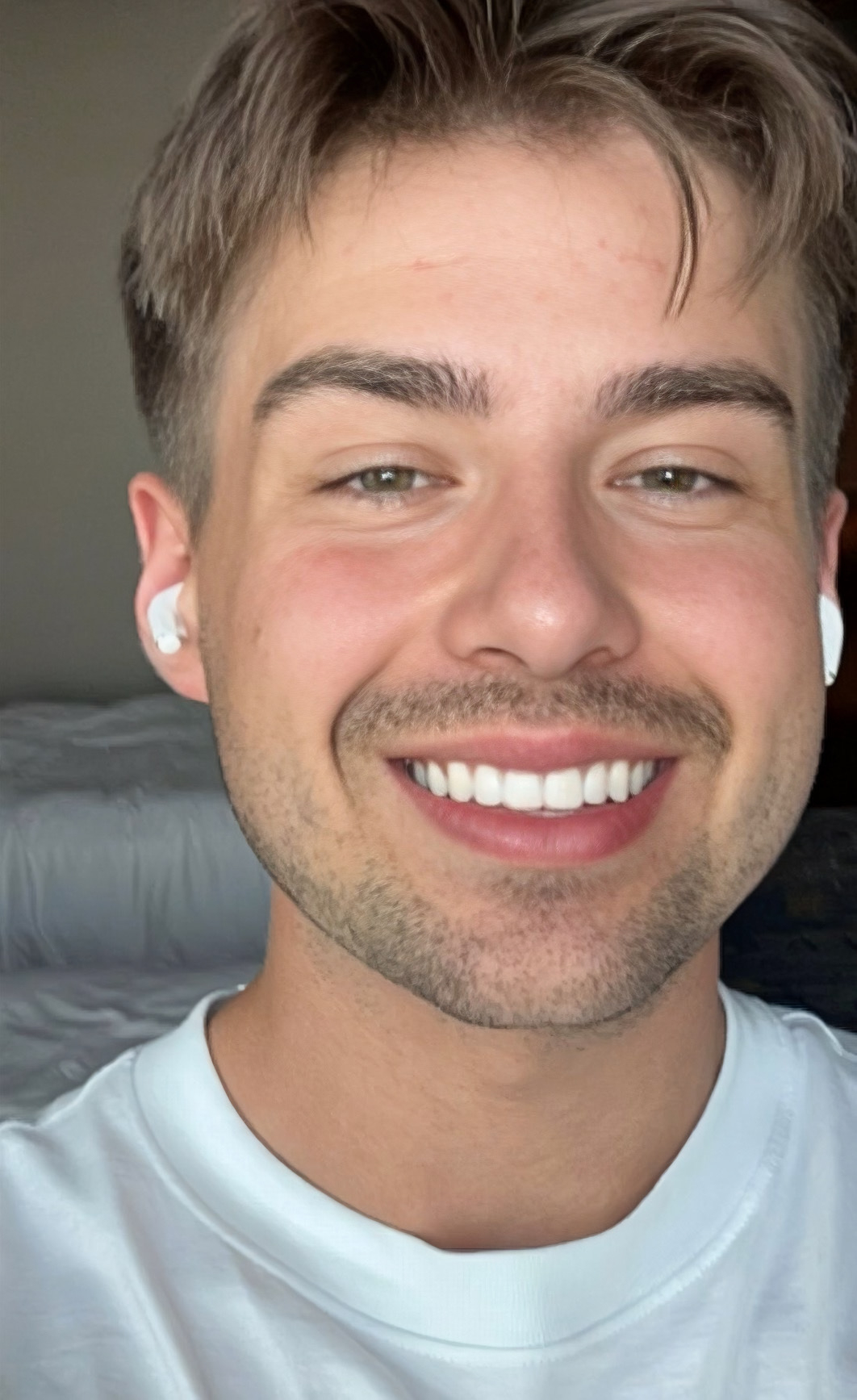 Mitarbeiter Mikkel hält die Kamera für ein Selfie, blickt direkt hinein und lächelt. Er trägt Kopfhörer.