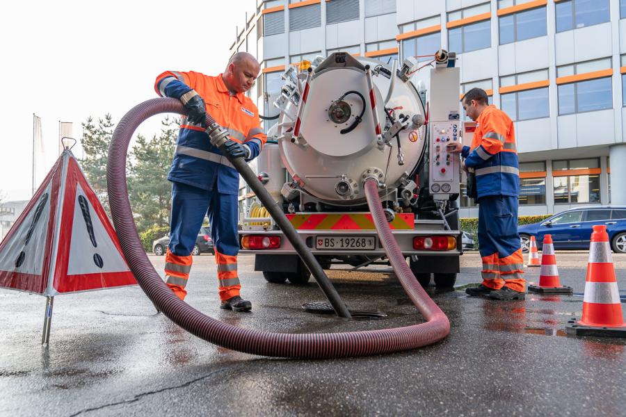 Zwei Männer reinigen den Kanal von der Oberfläche her