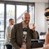 Oli lächelnd in der Agentur mit Kaffetasse in der Hand
